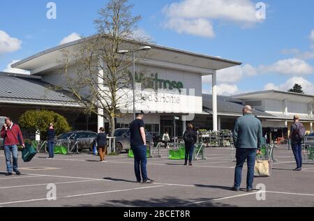 Les clients qui font la queue à 2 mètres d'intervalle dans un parking attendent d'entrer dans un supermarché pour acheter des provisions au Royaume-Uni pendant la pandémie de Covid19 de Coronavirus Banque D'Images