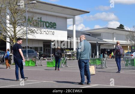 Les clients qui font la queue à 2 mètres d'intervalle dans un parking attendent d'entrer dans un supermarché pour acheter des provisions au Royaume-Uni pendant la pandémie de Covid19 de Coronavirus Banque D'Images