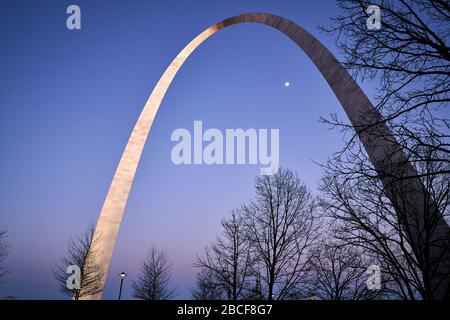 St Louis Missouri, États-Unis – 6 mars 2020 : l'arche de la porte d'entrée ; les visiteurs marchant le long de la ou des voies de la porte d'entrée au coucher du soleil tout en regardant la lune passer sous Banque D'Images