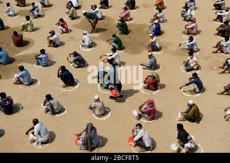 Dhaka, Bangladesh - 04 avril 2020: Les sans-abri bangladais attendent dans une file d'attente d'obtenir de l'aide pendant le verrouillage national imposé comme mesure aux précédent Banque D'Images
