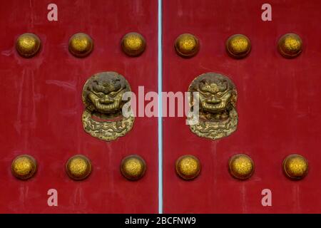 Têtes et clous en or orné fixés à une paire de portes rouges dans la Cité interdite, Beijing, Chine. Banque D'Images