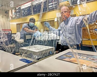 Les employés de la poste portant des gants et des masques apportent la pluie ou l'éclat du courrier... aussi en cas de pandémie. Bureau de poste à Arlington, Texas, avec une feuille de plastique accrochée au plafond entre les employés de poste et les clients. Petite ouverture pour le courrier. Un employé portant son masque pour conduire une moto pour protéger contre le froid. Banque D'Images