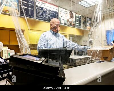 Les employés de la poste portant des gants et des masques apportent la pluie ou l'éclat du courrier... aussi en cas de pandémie. Bureau de poste à Arlington, Texas, avec une feuille de plastique accrochée au plafond entre les employés de poste et les clients. Petite ouverture pour le courrier. Un employé portant son masque pour conduire une moto pour protéger contre le froid. Banque D'Images