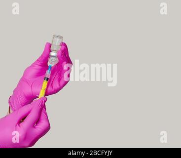 Préparation d'une injection. Prélèvement de médicaments du pot dans la seringue. Mains dans des gants en caoutchouc violet. Banque D'Images