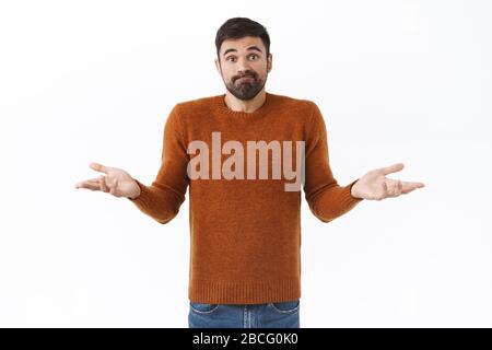 Portrait d'un homme barbu méchant et perplexe, haussant les mains sur le côté, ne sait pas quoi faire, se tenant indécisive, a besoin d'aide Banque D'Images