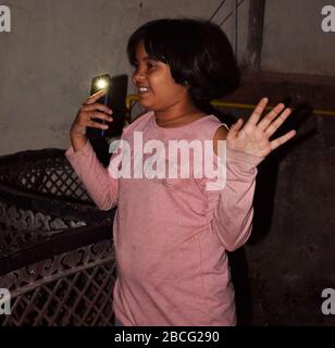 PM Modi appel - une fille indienne clignotant Mobile lumière dans balcon comme un respect pour tous les travailleurs des services essentiels qui risquent la vie pour le virus de Corona Banque D'Images