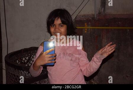 Une fille indienne qui clignote sur le mobile dans le balcon la nuit en appel par PM Narendra Modi pour montrer la solidarité avec la nation contre le virus Corona lutte Banque D'Images