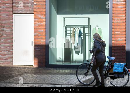 Femme portant un masque de visage marchant à travers le centre-ville vide de Veenendaal, aux Pays-Bas, où la plupart des magasins ont dû fermer à cause du coronavirus Banque D'Images