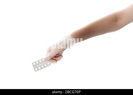 Prendre des pilules. Une main dans un gant en latex transparent blanc maintient un paquet de pilules. Les comprimés sont petits et blancs. La photo sur l'isolat blanc. Banque D'Images