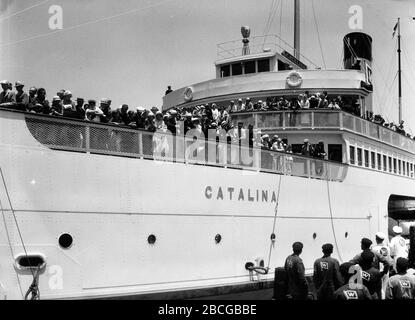 Les passagers regardent depuis les ponts du SS Catalina, également connu sous le nom de Great White Steamer, amarré à Avalon, Santa Catalina Island, Californie, 1931. Photographie par Burton Holmes. Banque D'Images