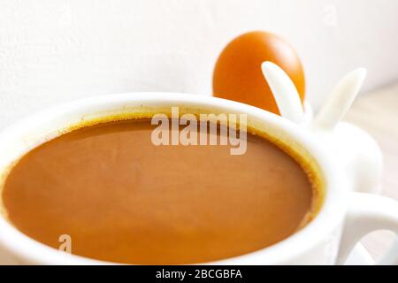 Café avec tasse à lait sur fond blanc. Porte-œufs de lapin. Concept de petit déjeuner de Pâques. Gros plan Banque D'Images