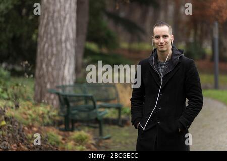 Beau jeune homme avec écouteurs dans Autumnal Park Banque D'Images