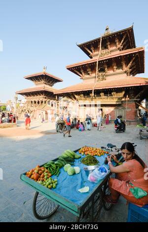 PATAN, NÉPAL - 29 juillet 2015 : un vendeur de rue vend des greens devant les temples de la place Patan Durbar, Katmandou, Népal Banque D'Images