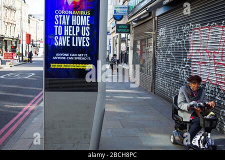 Londres Royaume-Uni 4 avril 2020 une femme sur un scooter de mobilité passe devant une nouvelle publicité de marque NHS avec l'avertissement sans à-propos « si vous sortez, vous pouvez la diffuser. Les gens mourront. » Crédit: Thabo Jaiyesimi/Alay Live News Banque D'Images