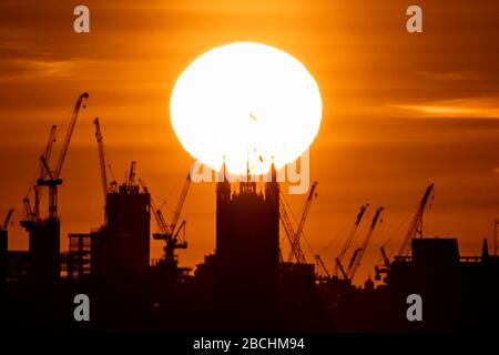 Londres, Royaume-Uni. 4 avril 2020. Coronavirus : un soleil chaud en soirée se couche sur la Tour Victoria de Westminster. Les Britanniques ont été invités à ne pas laisser le temps chaud du week-end les extraire de leur maison, afin de réduire la propagation du coronavirus. Avec les prévisions du Royaume-Uni de profiter du soleil samedi et dimanche, le premier ministre Boris Johnson et le secrétaire à la santé Matt Hancock ont déclaré que le public devait résister à l'envie de bafouer les règles de distanciation physique. Crédit: Guy Corbishley/Alay Live News Banque D'Images