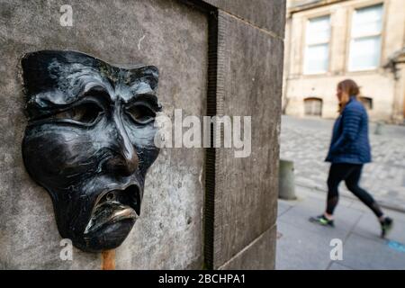 Masque théâtral relief en bronze avec un visage triste sur la tête de puits de High Street sur le Royal Mile à Édimbourg, en Écosse, au Royaume-Uni pour indiquer la tristesse de l'annulation du festival Edinburgh Flinge 2020. Banque D'Images