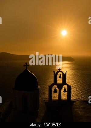 Santorin Grèce, un incroyable coucher de soleil donnant sur la mer d'Agean et la Caldera avec une église dôme bleue et trois clocher silhouetted contre le ciel. Banque D'Images