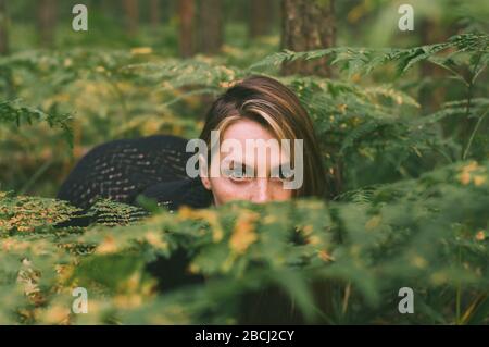 Portrait de la jeune belle fille en robe noire dans la forêt qui regarde l'appareil photo Banque D'Images
