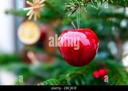 Macro closeup de traditionnel un nouvel an décoratif rouge pomme brillant ornement accroché sur arbre de Noël avec fond flou flou en hiver à Wa Banque D'Images