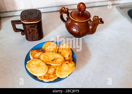 Théière traditionnelle ancienne rustique et mug de la région de Carpathe en Ukraine avec plaque de crêpes au fromage frit sur table Banque D'Images