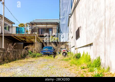 Quartier résidentiel de Kyoto au printemps au Japon avec de vieilles voitures par des maisons dans le jardin de l'allée et la moto le jour ensoleillé Banque D'Images