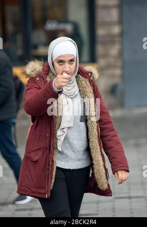 Une fille musulmane portant un pashmina et un manteau d'hiver, pointant avec son doigt. Place Taksim, Istanbul. Turquie Banque D'Images
