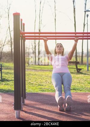 Jeune femme faisant un pull-UPS australien dans le parc Banque D'Images