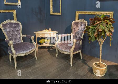 Coin chambre avec mobilier rétro. Chaises anciennes, petite table et cadres vides sur les murs. Banque D'Images