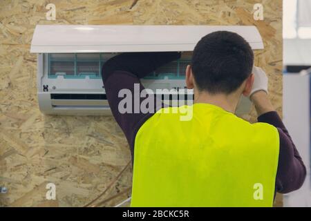 Supports de travailleur et connecte le conditionneur d'air sur le mur de la maison Banque D'Images