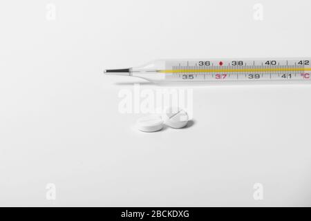 Un tas de pilules et de comprimés sur un fond blanc. Isolé. Espace de copie. Macro de capsules blanches sur fond blanc et thermomètre. Traitement de la grippe froide Banque D'Images