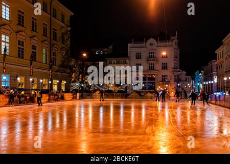 Lviv, Ukraine - 27 décembre 2019: Patinoire de la place du marché de la vieille ville à Lvov la nuit avec éclairage de Noël et patinage des gens la nuit Banque D'Images