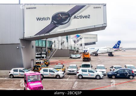 Varsovie, Pologne - 23 janvier 2020: L'aéroport international de Chopin pendant la journée avec des voitures par terminal gate et la publicité pour Samsung Watch Banque D'Images