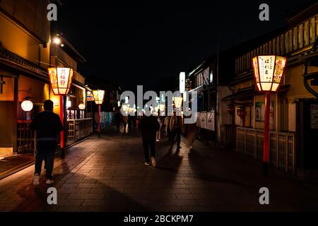 Kyoto, Japon - 9 avril 2019 : ruelle arrière étroite dans le quartier de Gion la nuit avec les gens marchant et rangée de lanternes rouges illuminées Banque D'Images