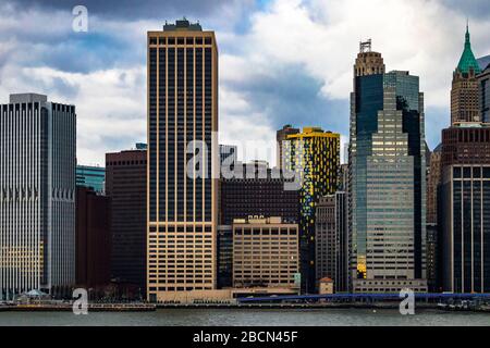 Vue sur les bâtiments du front de mer de New York de l'autre côté de la rivière East, en journée nuageux; vue sur le 55 bâtiment de la rue Water. Banque D'Images