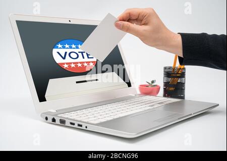 Concept de vote en ligne avec un homme avec un bulletin de vote en main mettant un bulletin de vote vers le moniteur d'ordinateur. Banque D'Images