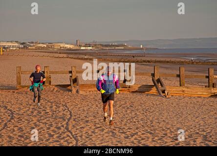 Portobello, Édimbourg, Écosse, Royaume-Uni. 5th avril 2020. Lever du soleil sur la plage de Portobello, homme et femme en photo courant, avec diverses personnes nageant, marchant, et assis dans la contemplation sur la plage de sable. Banque D'Images