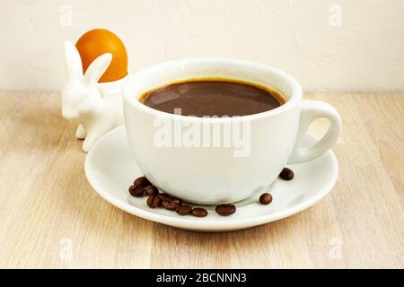 Tasse à café, soucoupe, haricots, porte-œufs de lapin. Concept de petit déjeuner de Pâques Banque D'Images