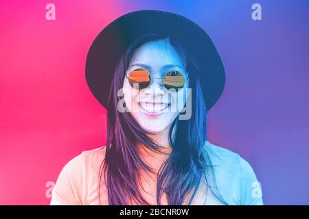 Portrait d'une heureuse fille asiatique souriant avec des lunettes de soleil vintage - jeune femme chinoise qui s'amuse se posant devant l'appareil photo - mode, tendance et moulin Banque D'Images