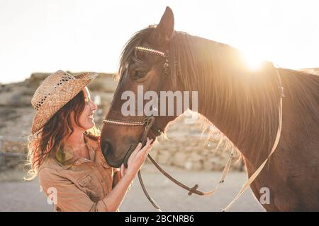 Jeune femme payeuse jouant avec son cheval sans amertume dans une journée ensoleillée à l'intérieur du ranch corral - concept sur l'amour entre les gens et les animaux - se concentrer sur la fille f Banque D'Images