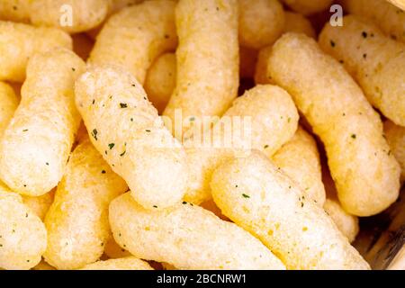 Chips croustillantes aromatisées à l'oignon jaune croquant macro closeup. Feuilletés au fromage de maïs frais, au lait, au curl avec en-cas rapide aromatisants dans un paquet ouvert Banque D'Images