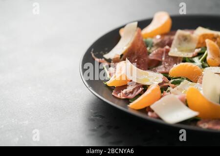 Salade avec prosciutto, mandarines et fromage d'époque avec espace de copie Banque D'Images