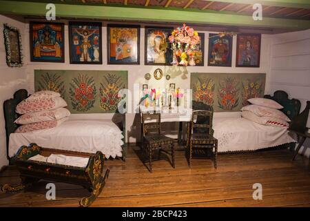 L'intérieur du Musée ethnographique (Muzeum Etnograficzne) à Cracovie, en Pologne, maison traditionnelle polonaise en bois rural avec table, lits, berceau, religii Banque D'Images