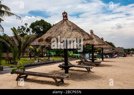 Une plage avec des abris dans le style balinais traditionnel, Bali, Indonésie Banque D'Images
