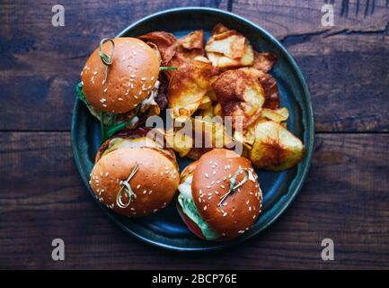 Trois mini-hamburgers différents avec du boeuf et des légumes et des chips dans une assiette de nourriture américaine Banque D'Images