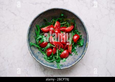 Salade de légumes saine avec tomates cerises et roquette à l'huile d'olive et épices dans un bol vue sur le dessus de la nourriture végétalienne Banque D'Images