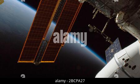 ISS - 10 mars 2020 - le navire de réapprovisionnement SpaceX Dragon (à droite) et une paire des principaux panneaux solaires de la Station spatiale internationale annoncent une randonnée dans un Banque D'Images