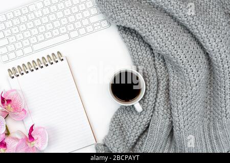 Flatlay de lieu de travail confortable avec café chaud, ordinateur portable et carnet de notes et fleur. Travail de la maison. Écriture. Concept chaud par temps froid Banque D'Images