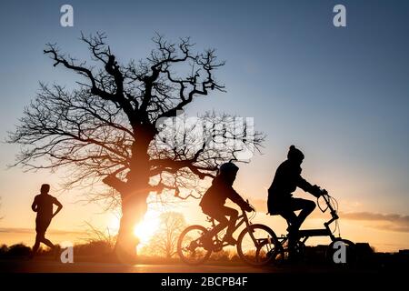 Les amis se rassemblent sur Clapham Common avec un coureur (sous le verrou des restrictions du virus Corona Covid 19) sous un coucher de soleil spectaculaire en mars 2020 Banque D'Images