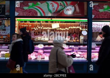 Les clients qui font des achats dans un salon de saucisses hongrois traditionnel dans le Central Market Hall de Budapest, en Hongrie, en hiver Banque D'Images