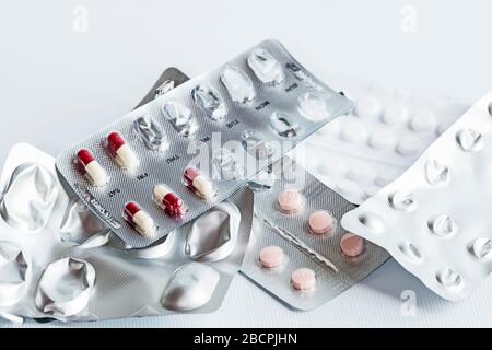Cinq paquets de médicaments différents prescrits après une crise cardiaque (infarctus du myocarde) dans des bandes de feuilles d'argent, disposés au hasard, fond blanc. Banque D'Images
